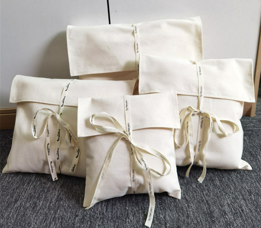 Natural canvas flap pouch with ribbon tie closure and folded flap, front view