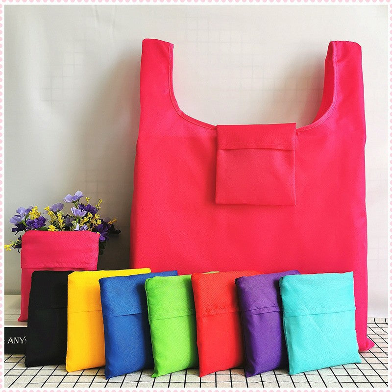 Foldable reusable shopping bag in assorted colors with front pocket, folded flat for storage
