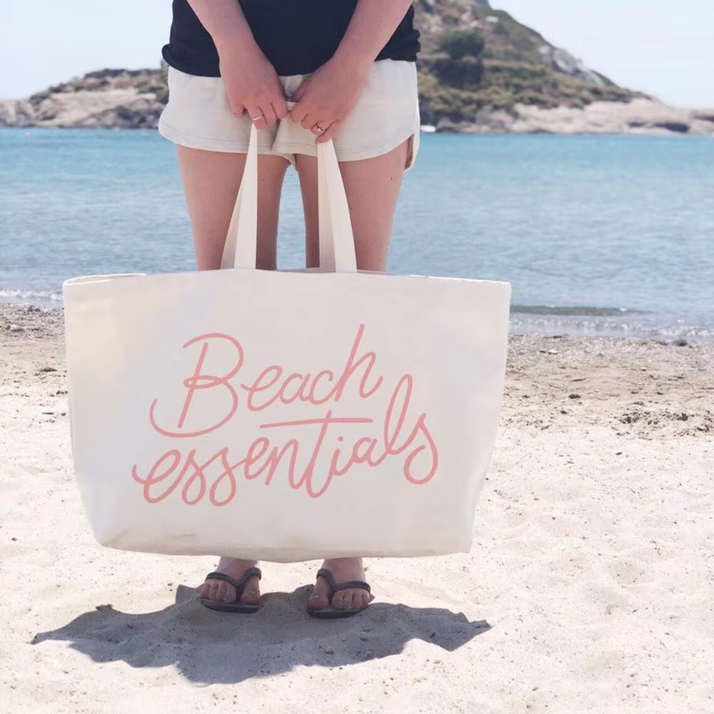 Cream canvas tote bag with Beach Essentials print for summer use
