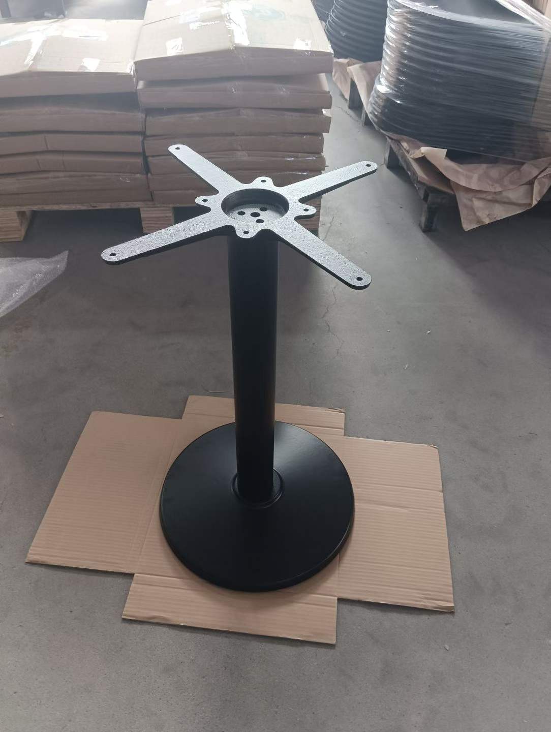 Close-up of the 4-hole mounting plate on a black metal single-column table base