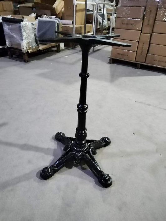 Close-up of cast iron table base showing cross mounting plate and black finish