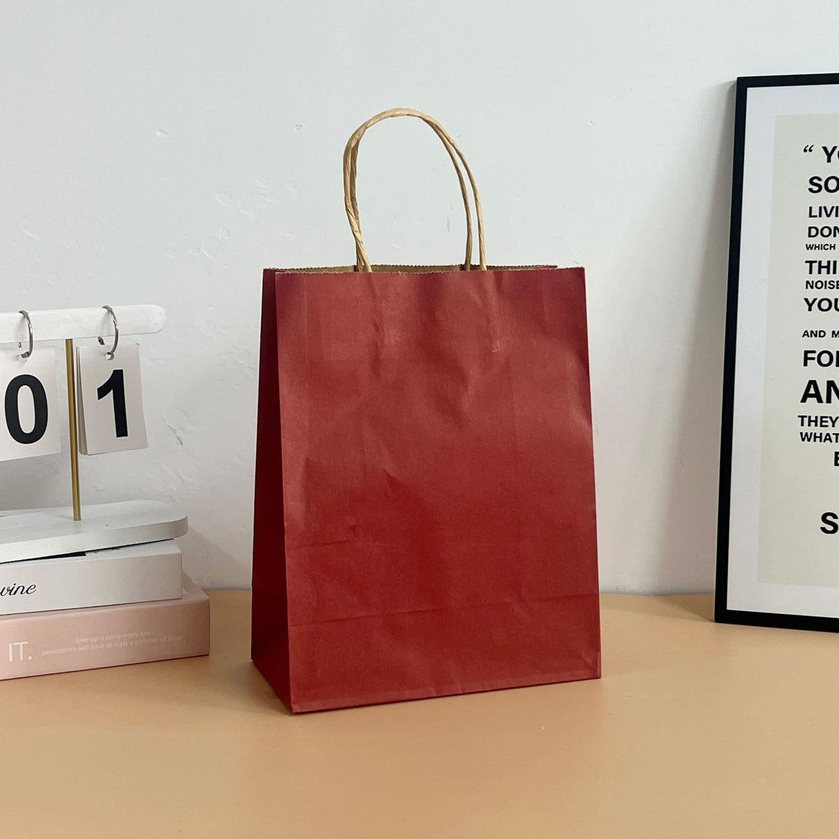 Colored paper tote bags with paper rope handles standing upright on a counter