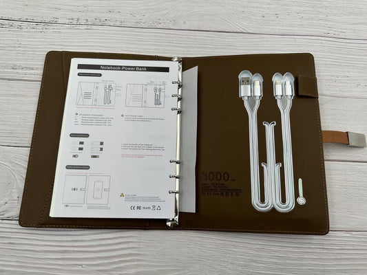 Black multifunctional business notebook with built-in power bank and data cable on a desk