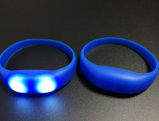 Close-up of the push-button glow control on a black silicone LED wristband