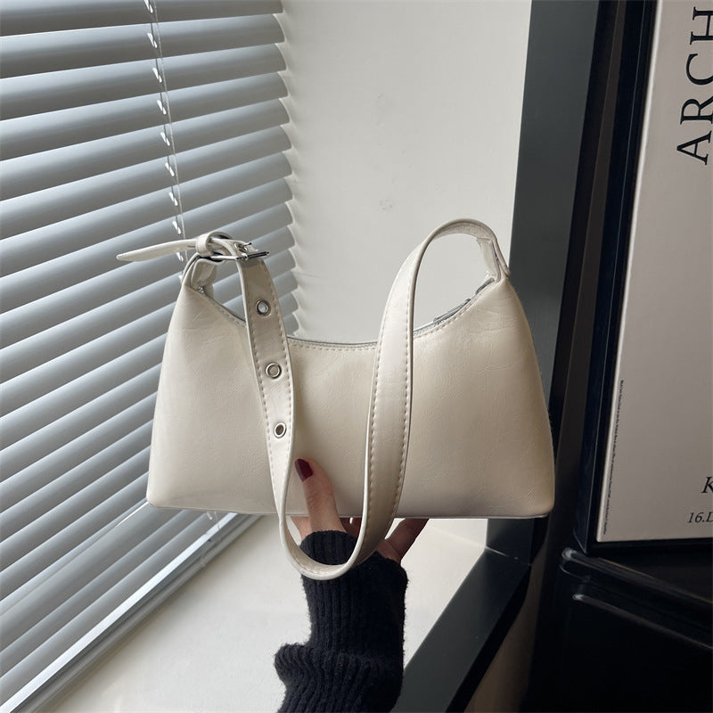Retro studded underarm bag in smooth black leather with half-moon shape and metal studded strap