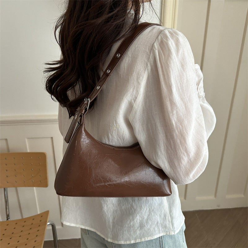 Close-up of silver metal studs and buckle on the shoulder strap of a retro underarm bag