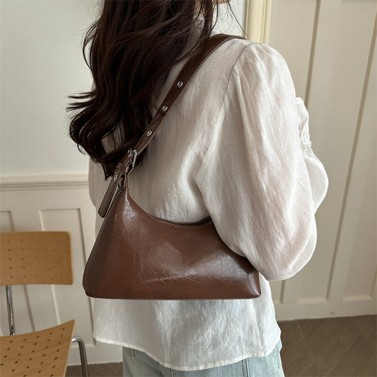Close-up of silver metal studs and buckle on the shoulder strap of a retro underarm bag