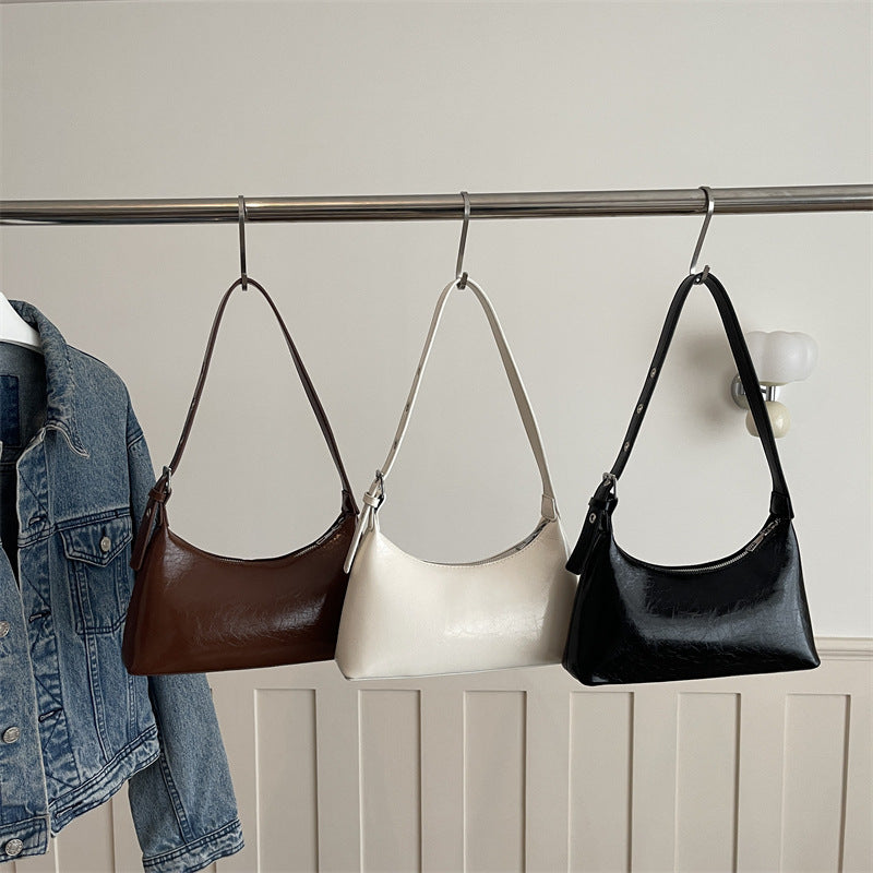 Black half-moon leather underarm bag with zipper closure and studded shoulder strap
