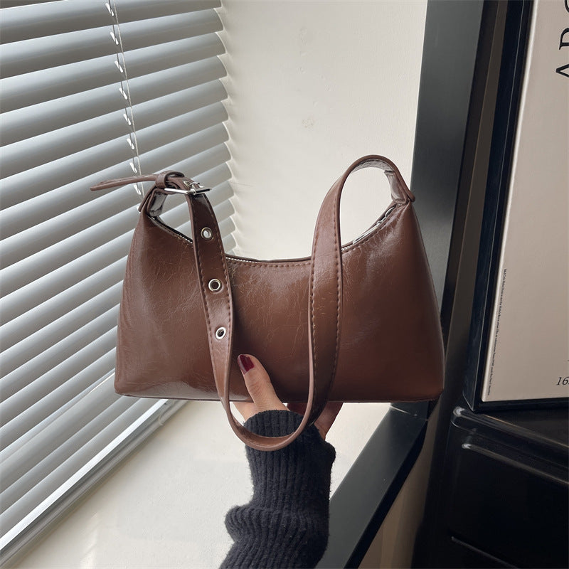 Glossy dark red leather underarm bag with metal studs and adjustable shoulder strap