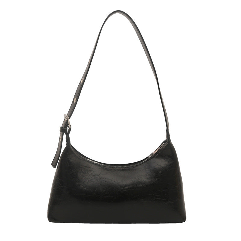 Retro studded shoulder bag in glossy black leather with zipper closure and half-moon silhouette